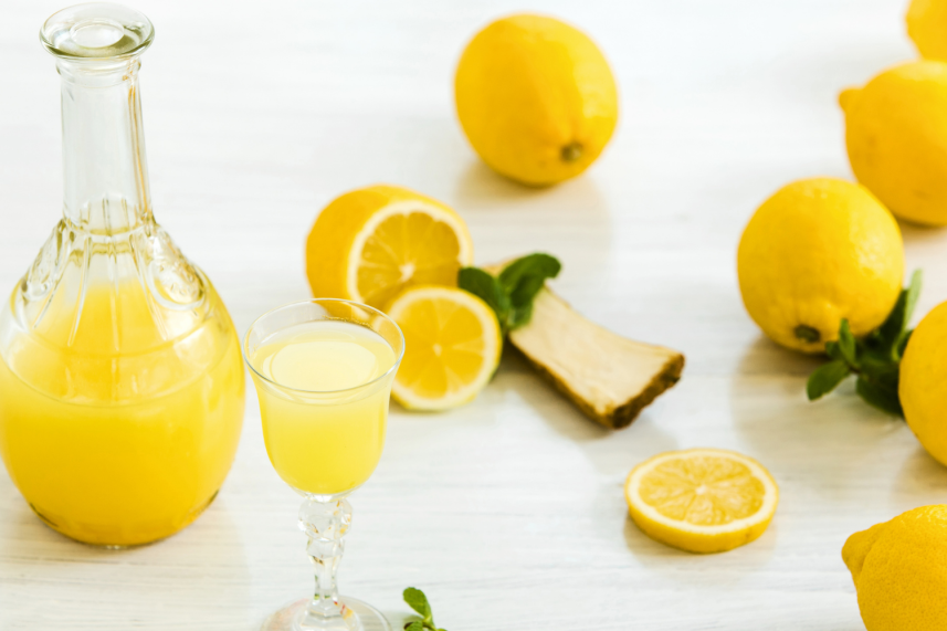 Jugo de naranja fresco con rodajas de limón en un fondo claro.