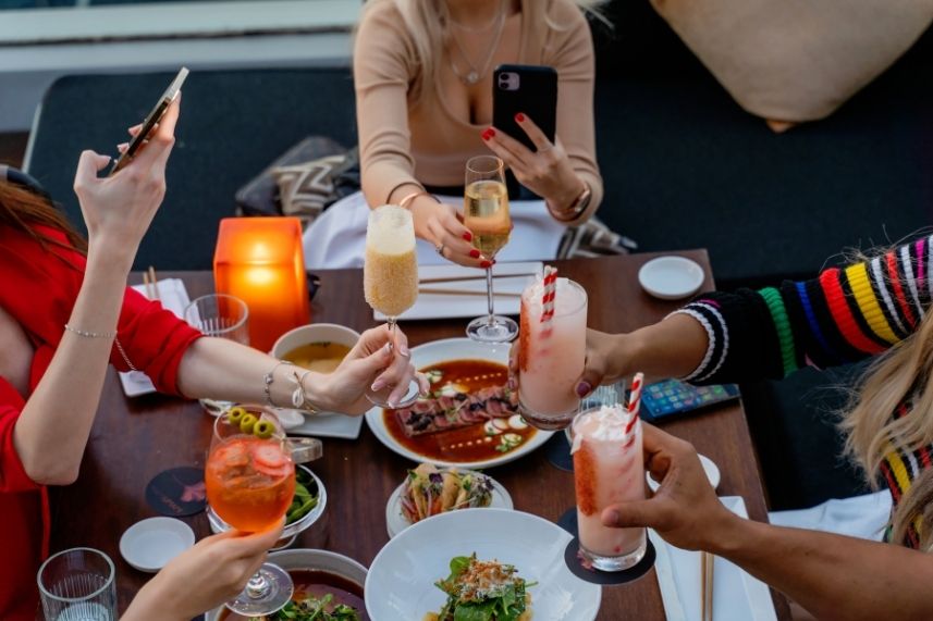 Varias personas levantan sus copas en un restaurante, disfrutando de una celebración amistosa.