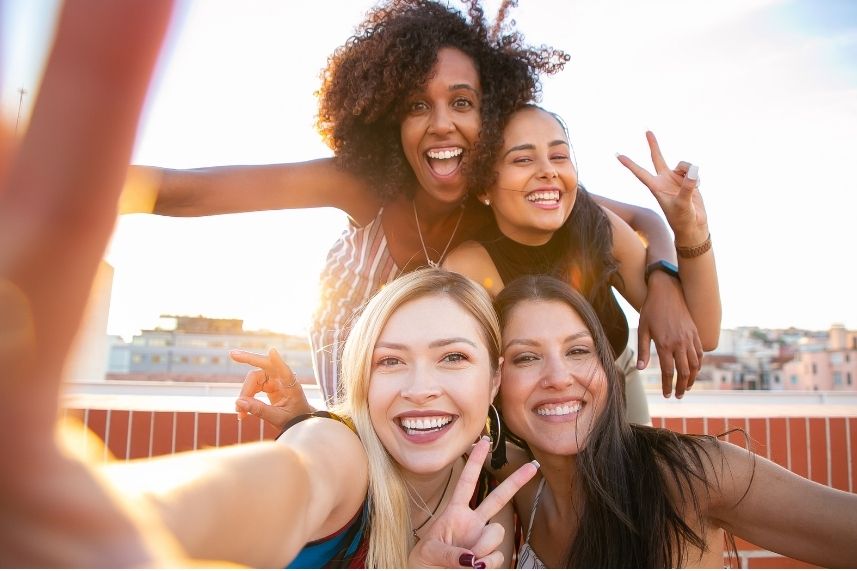 Cuatro mujeres se toman una selfie, todas sonriendo y disfrutando del momento juntas.