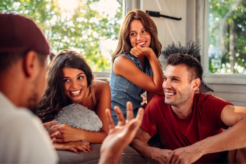 Varios amigos comparten un momento en el sofá, riendo y conversando animadamente.