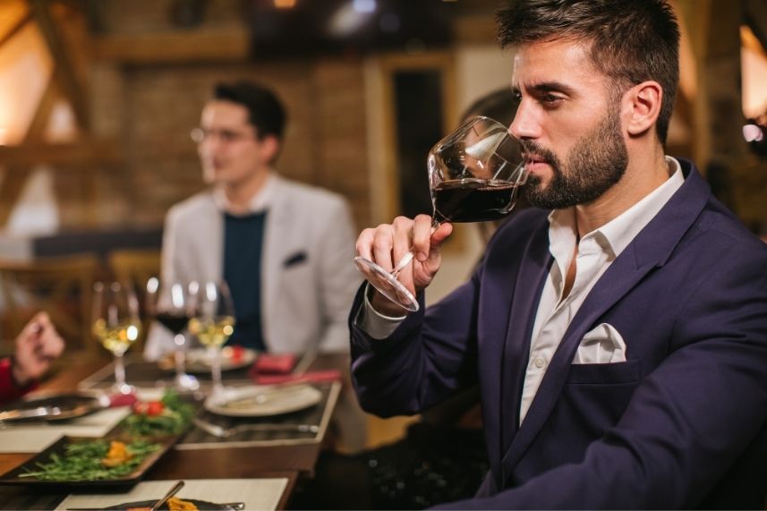 Un hombre bebe vino en un restaurante, rodeado de un ambiente acogedor.