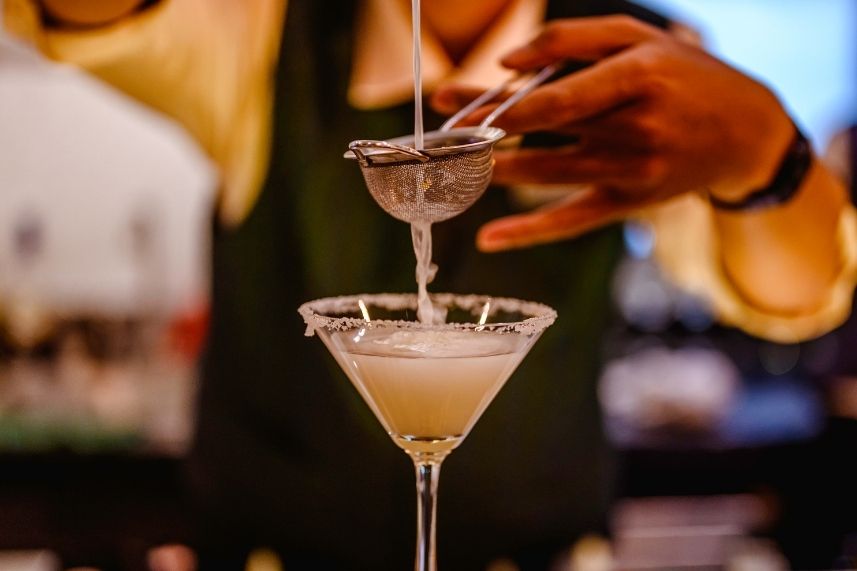 Un barman sirviendo un cóctel en una elegante copa de martini.