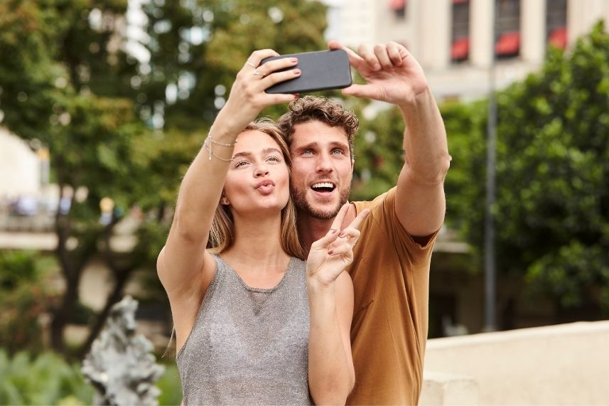 Un hombre y una mujer sonríen mientras se toman un selfie con su teléfono móvil.