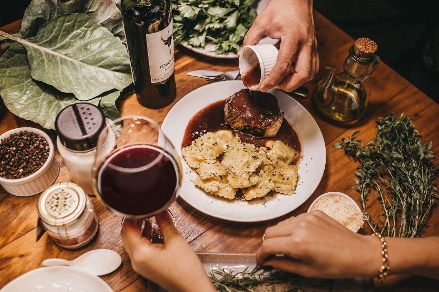 Mesa con comida deliciosa y copas de vino, creando un ambiente acogedor.