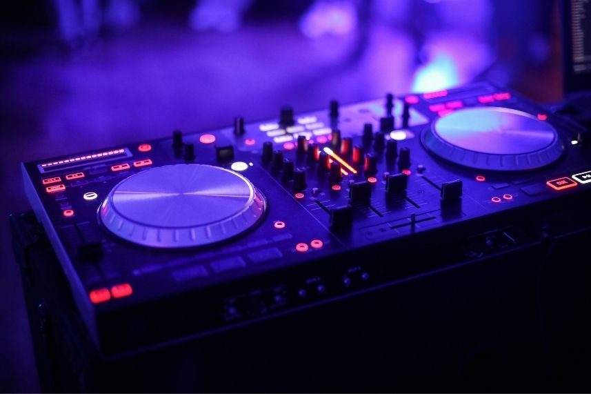 Mezclador de DJ con luces púrpuras, creando un ambiente vibrante en Sibari.