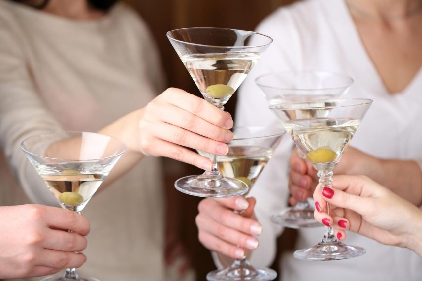 Un grupo de mujeres sonrientes sosteniendo copas de vino en un ambiente festivo.