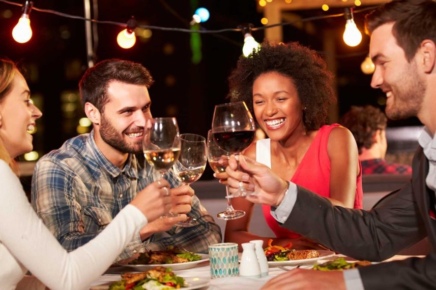 Un grupo de amigos brindando con copas de vino en un restaurante, sonriendo y disfrutando de su tiempo juntos.