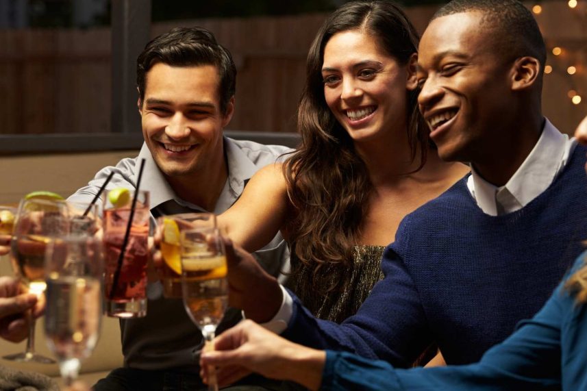 Amigos levantando sus bebidas en un brindis, sonriendo y disfrutando juntos.