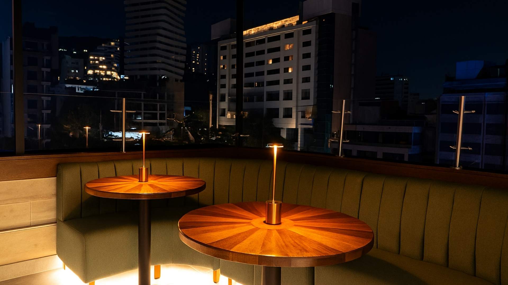 Dos lámparas sobre una mesa, con un fondo de ciudad iluminada al atardecer.